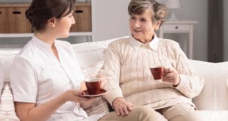 caregiver and senior woman having tea