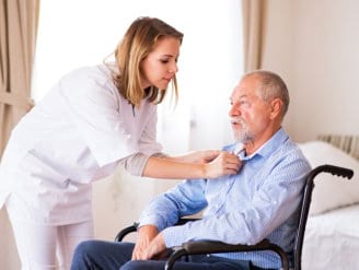 caregiver helping senior man in dressing